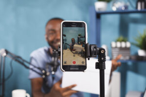 مرصد جروب 3 blogger making giveaway while live streaming smartphone screen closeup web content creator announcing contest showing prize gift using mobile phone tripod video recording scaled 1