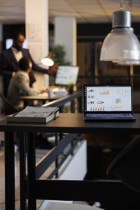 مرصد جروب 4 laptop computer with financial graphs screen standing table startup office coworkers discussing company strategy background employees working late night startup office scaled 1