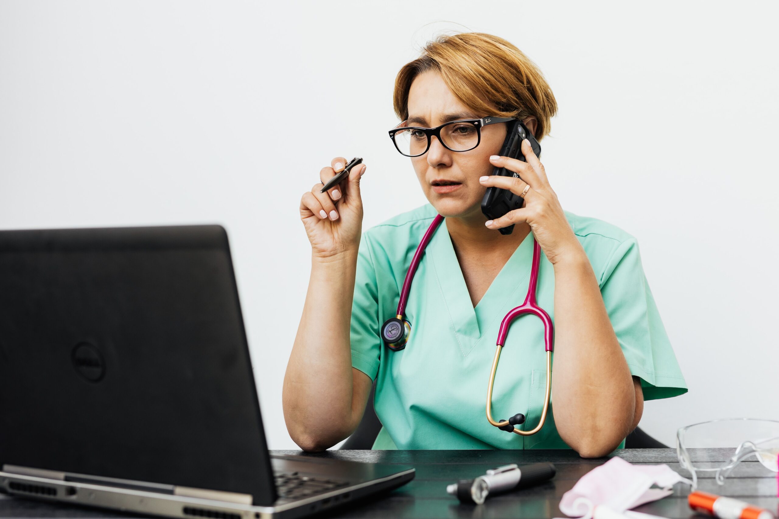 Healthcare provider reviewing patient outreach on a laptop and phone, representing AI search for medical practices