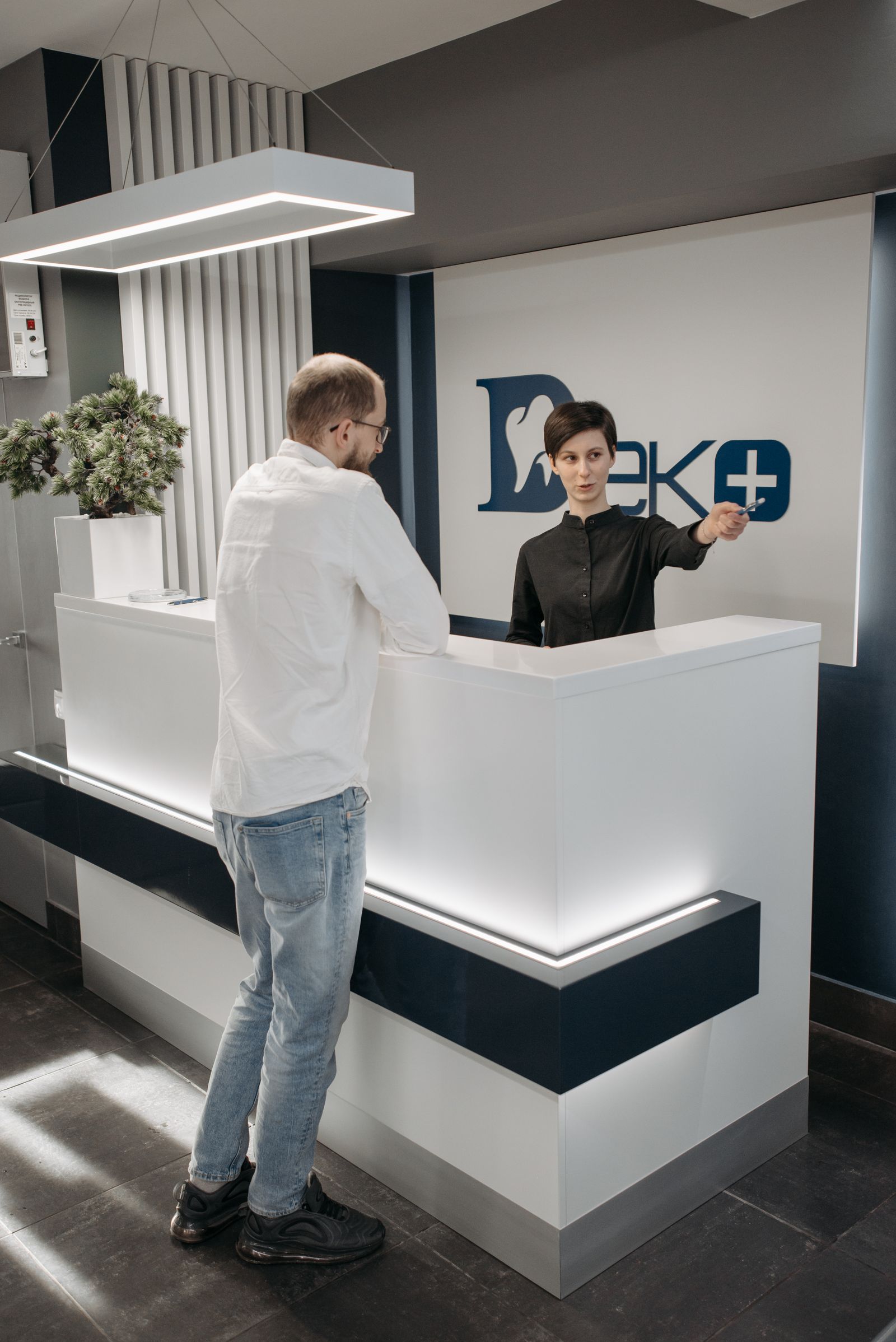 Receptionist assisting a patient at a modern dental clinic reception desk