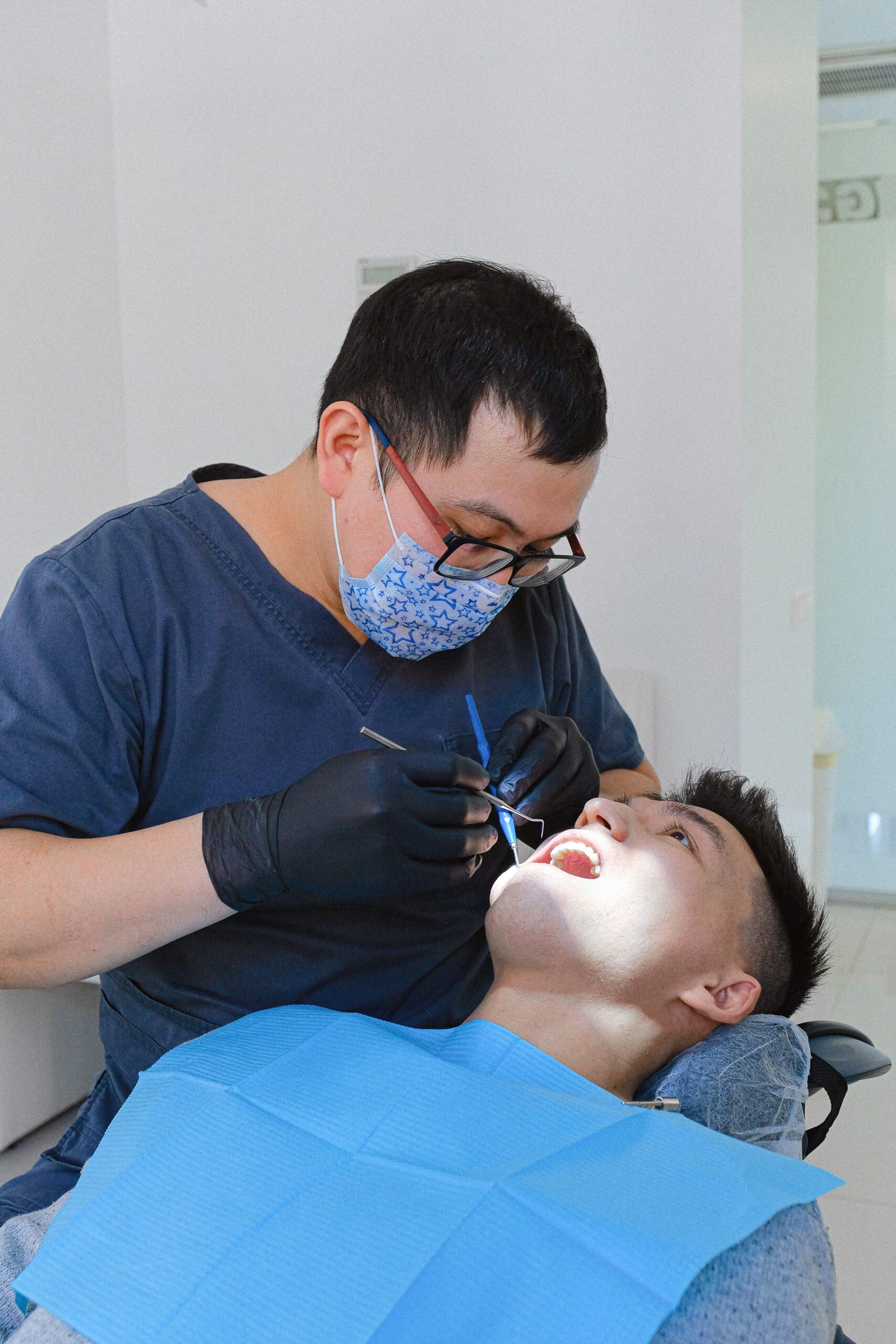 A dentist performing a routine checkup on a patient in a dental chair, the kind of visit that triggers a post-visit review request