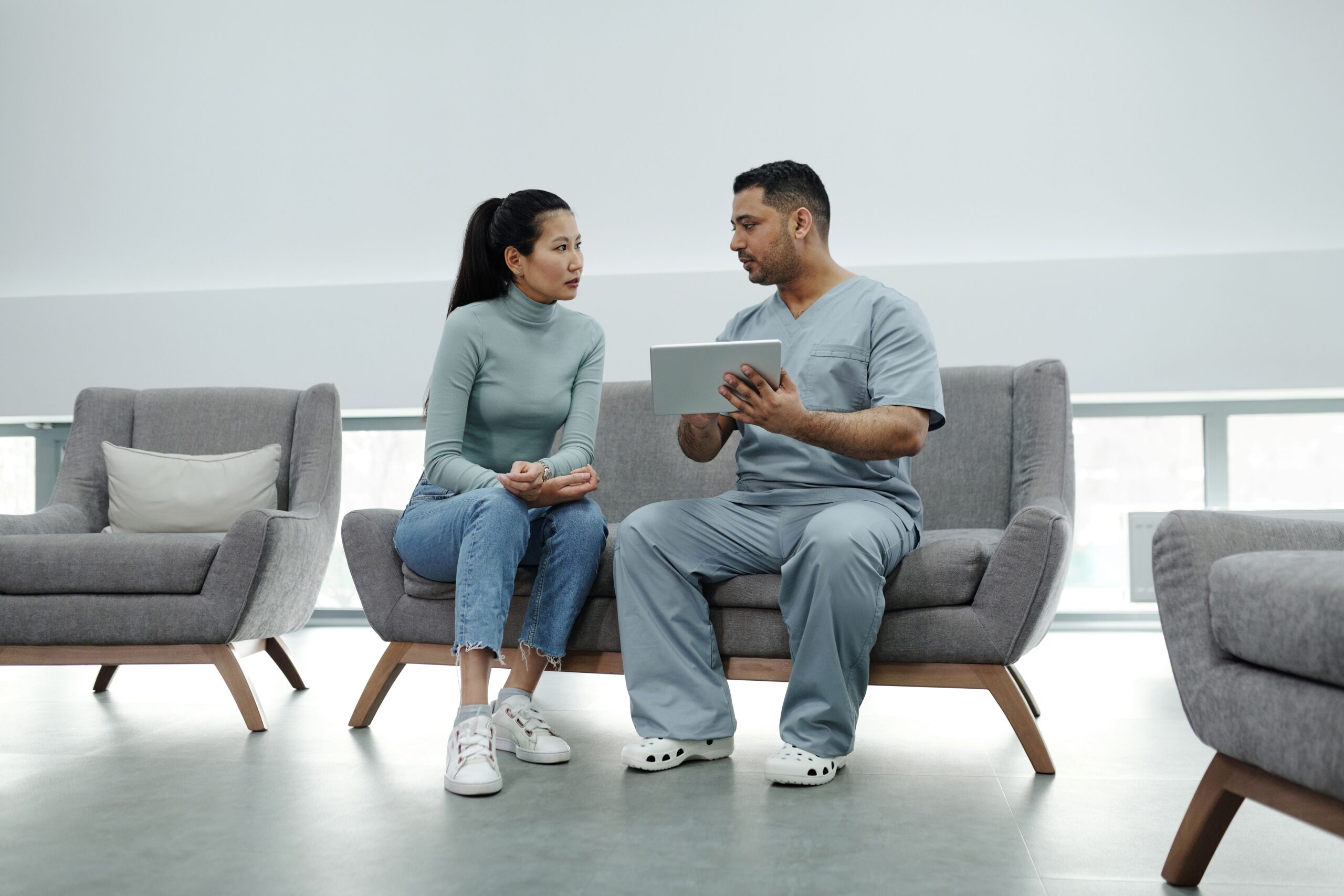 A healthcare provider consulting a patient with a tablet, representing the marketing platforms practices use to send review requests