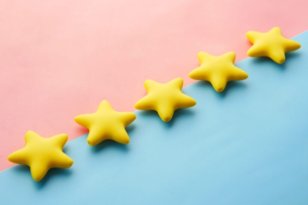 Five yellow stars on a pink and blue background, representing the FTC's review rating rules for medical and dental practices