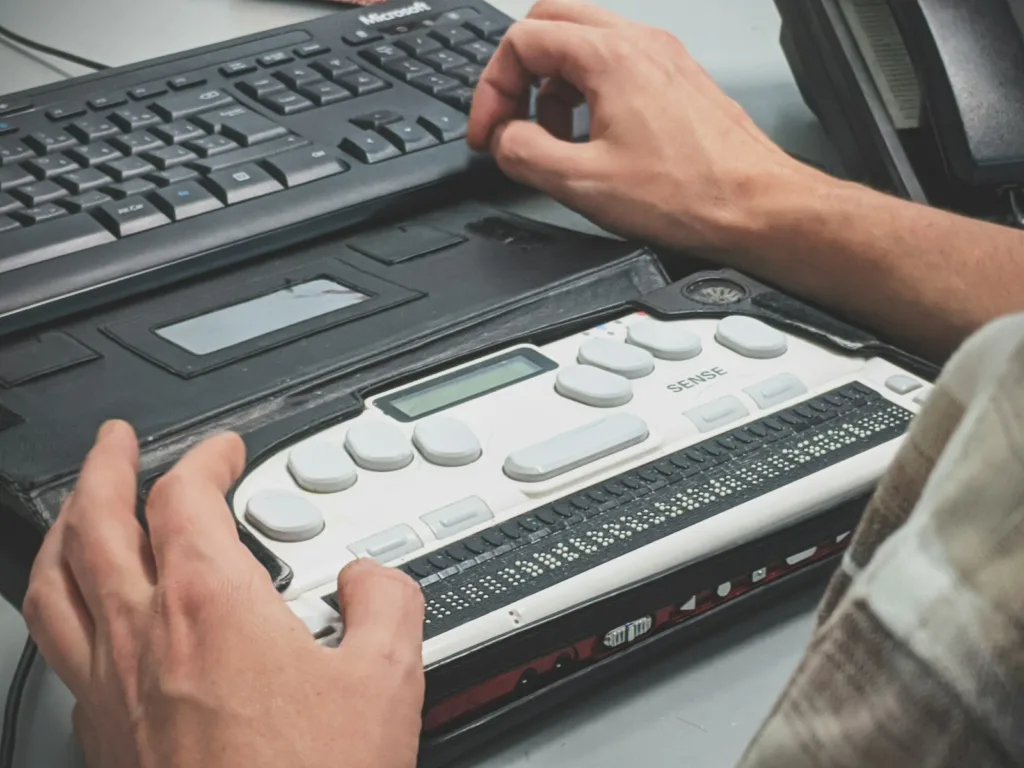 Person using a braille writer, representing digital accessibility for people who are blind or visually impaired