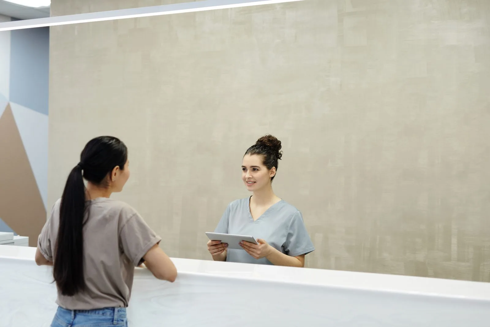 Front desk staff member assisting a patient, representing where lead follow-up should happen instead of inside a Meta lead form
